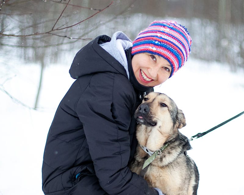 Волонтер приюта для бездомных животных в обнимку с бездомной беспородной собакой из приюта